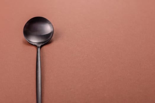 Empty metal spoon on a monochrome brown background. Cutlery on the dining table