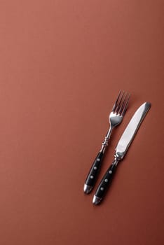 Knife and fork, cutlery on a brown dining table. Utensils and crockery for preparing dinner