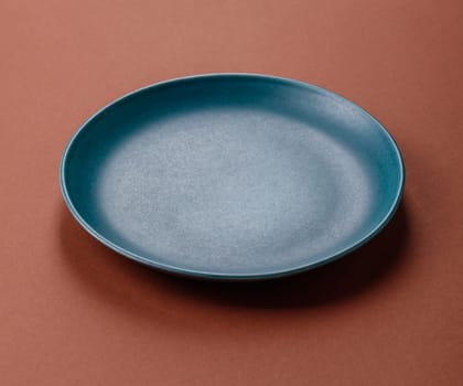 Empty ceramic plate on a monochrome brown background. Empty plate with cutlery on a dining table