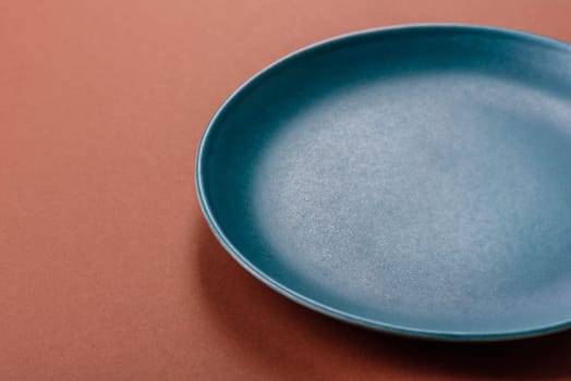 Empty ceramic plate on a monochrome brown background. Empty plate with cutlery on a dining table
