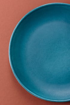 Empty ceramic plate on a monochrome brown background. Empty plate with cutlery on a dining table