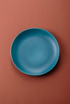 Empty ceramic plate on a monochrome brown background. Empty plate with cutlery on a dining table