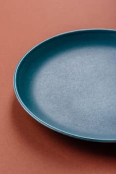 Empty ceramic plate on a monochrome brown background. Empty plate with cutlery on a dining table