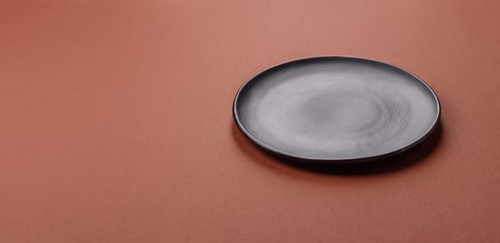 Empty ceramic plate on a monochrome brown background. Empty plate with cutlery on a dining table