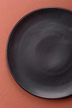 Empty ceramic plate on a monochrome brown background. Empty plate with cutlery on a dining table