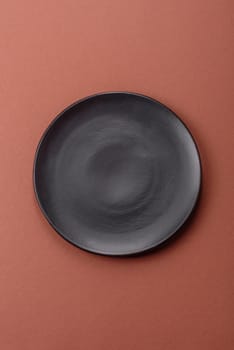 Empty ceramic plate on a monochrome brown background. Empty plate with cutlery on a dining table