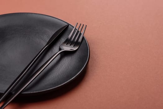 Empty ceramic plate on a monochrome brown background. Empty plate with cutlery on a dining table