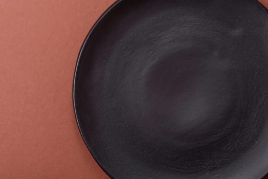 Empty ceramic plate on a monochrome brown background. Empty plate with cutlery on a dining table