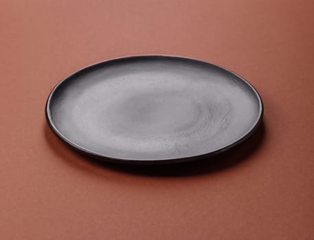 Empty ceramic plate on a monochrome brown background. Empty plate with cutlery on a dining table