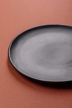 Empty ceramic plate on a monochrome brown background. Empty plate with cutlery on a dining table