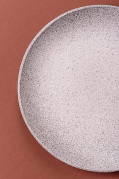 Empty ceramic plate on a monochrome brown background. Empty plate with cutlery on a dining table