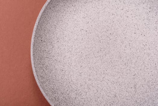 Empty ceramic plate on a monochrome brown background. Empty plate with cutlery on a dining table
