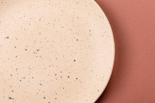 Empty ceramic plate on a monochrome brown background. Empty plate with cutlery on a dining table