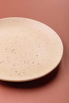 Empty ceramic plate on a monochrome brown background. Empty plate with cutlery on a dining table