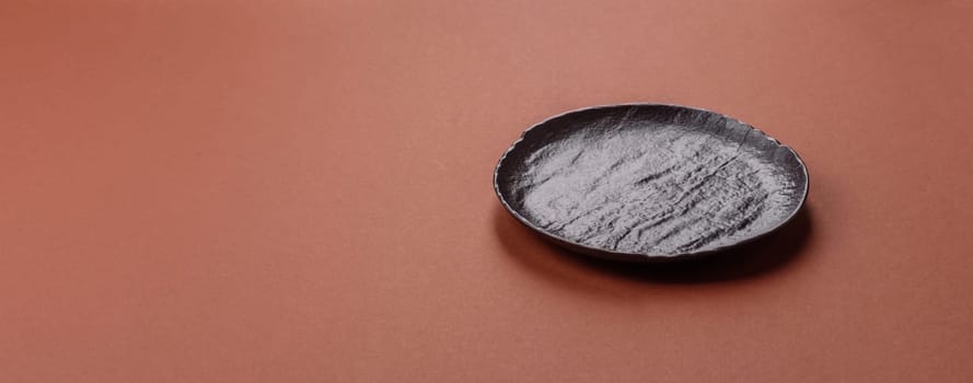 Empty ceramic plate on a monochrome brown background. Empty plate with cutlery on a dining table