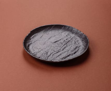 Empty ceramic plate on a monochrome brown background. Empty plate with cutlery on a dining table