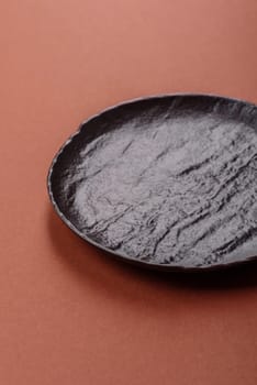 Empty ceramic plate on a monochrome brown background. Empty plate with cutlery on a dining table