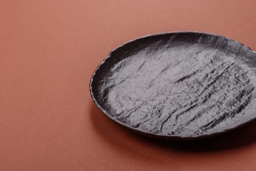 Empty ceramic plate on a monochrome brown background. Empty plate with cutlery on a dining table