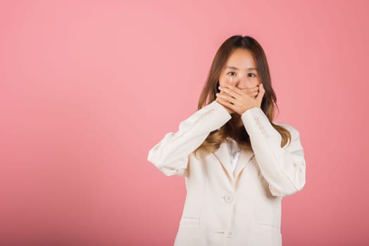 Asian happy portrait beautiful young woman standing smiling surprised excited her covering mouth with hands see only eyes and looking to camera on pink background with copy space for text