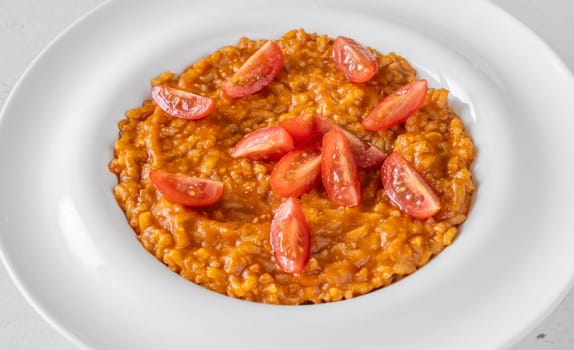 Tomato risotto plated simply with cherry tomato garnish and vibrant warmth