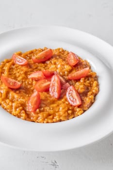 Tomato risotto plated simply with cherry tomato garnish and vibrant warmth