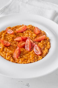 Tomato risotto plated simply with cherry tomato garnish and vibrant warmth