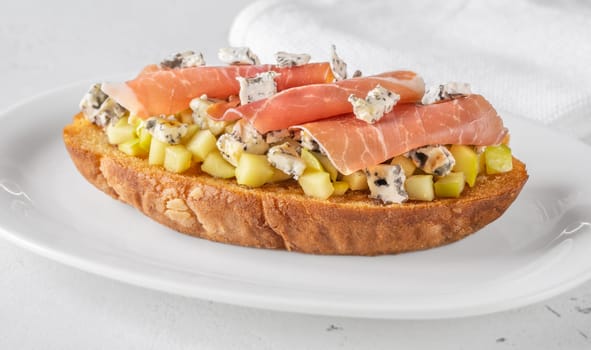 Warm sandwich stacked with creamy cheese, salty ham, sweet apple, and honey