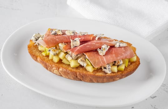 Warm sandwich stacked with creamy cheese, salty ham, sweet apple, and honey