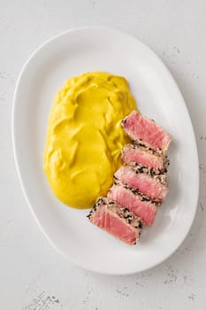 Crisp sesame tuna rests beside smooth cauliflower curry, balanced and visually refined