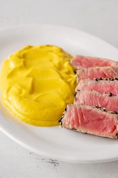 Crisp sesame tuna rests beside smooth cauliflower curry, balanced and visually refined