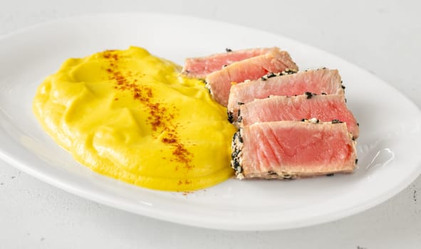 Crisp sesame tuna rests beside smooth cauliflower curry, balanced and visually refined
