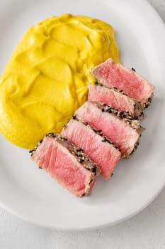 Crisp sesame tuna rests beside smooth cauliflower curry, balanced and visually refined