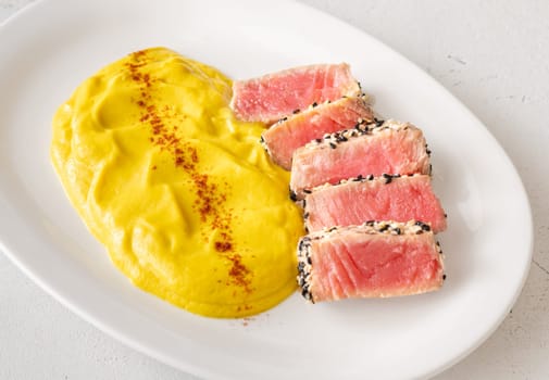 Crisp sesame tuna rests beside smooth cauliflower curry, balanced and visually refined