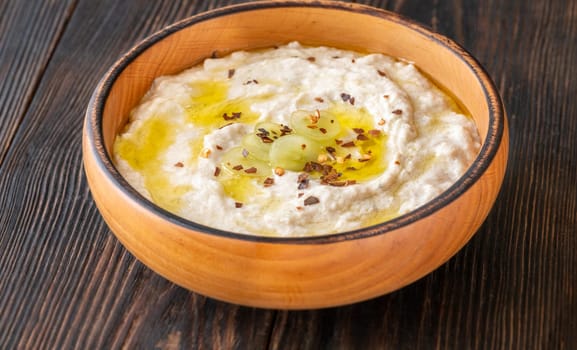 Roasted eggplant dip topped with chili flakes and oil in rustic setting