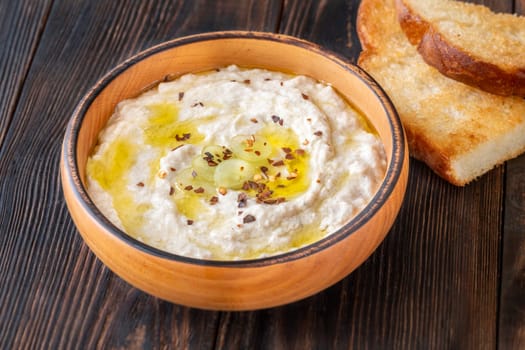 Roasted eggplant dip topped with chili flakes and oil in rustic setting