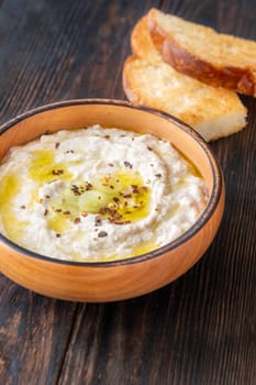 Roasted eggplant dip topped with chili flakes and oil in rustic setting