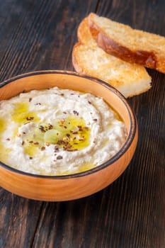 Roasted eggplant dip topped with chili flakes and oil in rustic setting