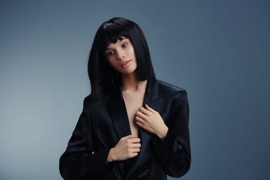 Black suit woman posing with hands on hips, looking off to the side, exuding confidence and professionalism in a studio setting