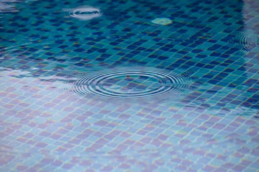 Soft ripples ripple through a clear blue swimming pool as sunlight sparkles on the water's surface. A moment of serene beauty invites peaceful contemplation and relaxation.