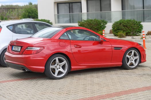 Gaziveren Cyprus -10.04.2025 A stunning red sports car stands parked beside modern buildings, capturing attention with its shiny exterior and elegant lines.