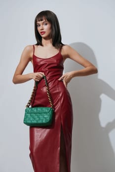 Red dress, green handbag, white wall, red purse a woman in a striking red dress holds a green handbag while standing in front of a white wall, with a red purse slung over her shoulder