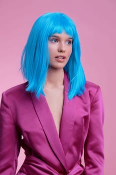 Woman with bright blue wig wearing pink suit, standing against pink background, exuding vibrant and playful energy, perfect for themes of fashion, individuality, and bold color contrast