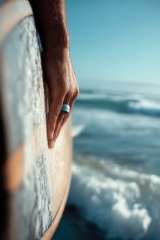 Surfer's hand gently gripping a surfboard above ocean waves, symbolizing freedom and adventure. Perfect visual for wellness campaigns, surfing promotion, beach activities, or travel themes