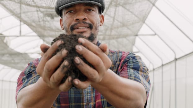 Farmer holding pile of arable black soil. Close up of expert hand of farmer checking soil health before growth a seed of vegetable, Business or ecology concept