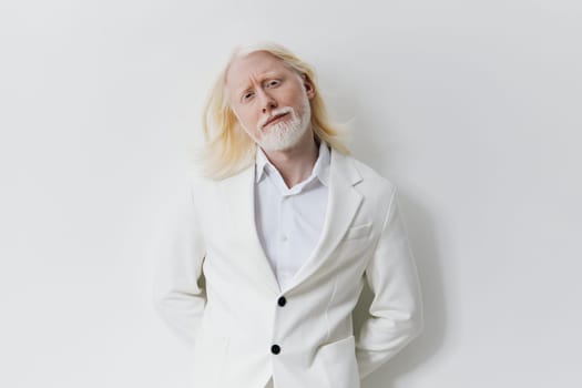 A fashionable male figure with striking white hair and beard, dressed in a chic white suit The image features a plain, light colored background, accentuating the man s sophisticated look and serene expression, embodying modern elegance and individuality