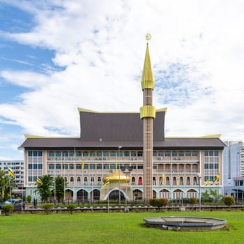 Visitors admire the stunning architecture of the Department of Syariah Affairs building in Bandar Seri Begawan, Brunei, showcasing its golden dome and intricate design under a clear sky