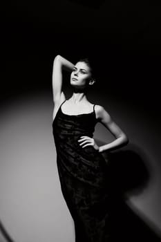 Black and white image of a sophisticated female model striking a pose, embodying elegance and fashion in a minimalist setting. Mood and style concept.