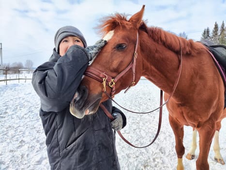 Individual enjoys a close moment with a horse in a snowy landscape, highlighting the bond between humans and animals.