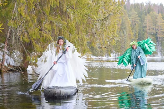 Two girls dressed in white and green costumes gracefully paddle on a serene lake, symbolizing the enchanting meeting of winter and spring.