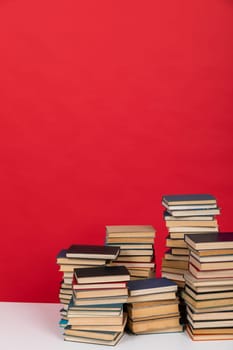 Stacks of educational books on the red background of the university library
